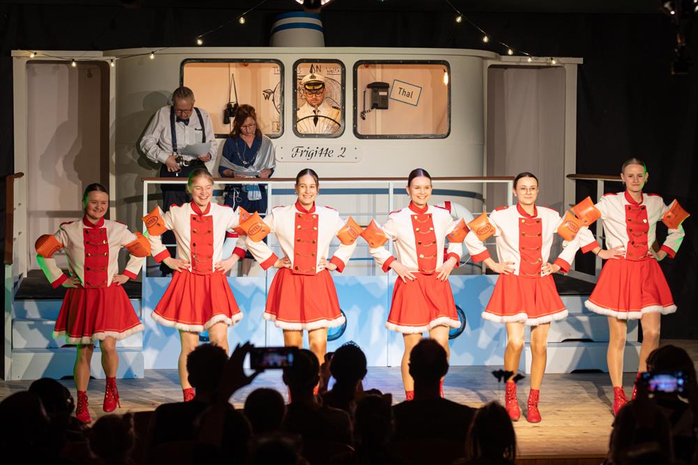 eine Gruppe von Menschen in rot-weißen Uniformen auf einer Bühne